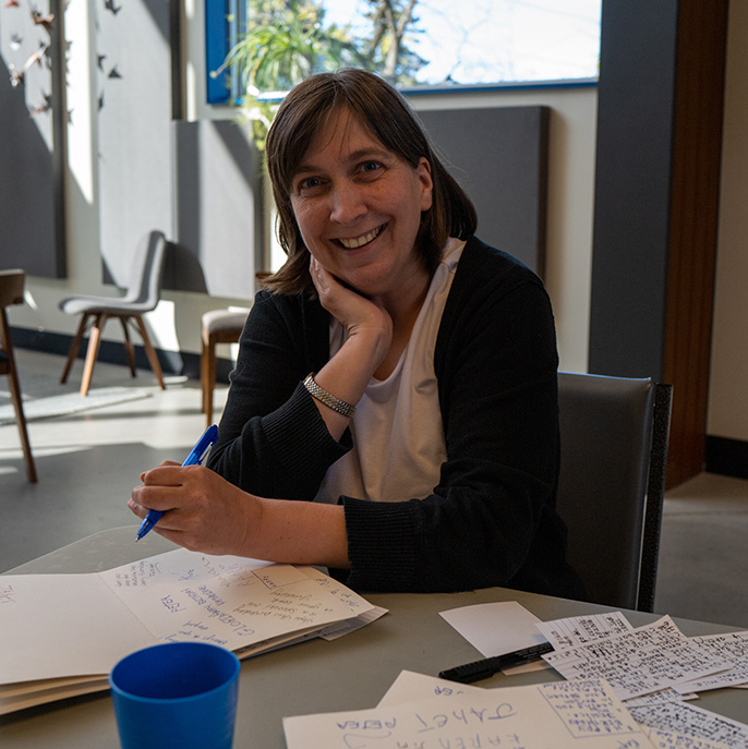 Photo of a woman from L'Arche London at a desk smiling