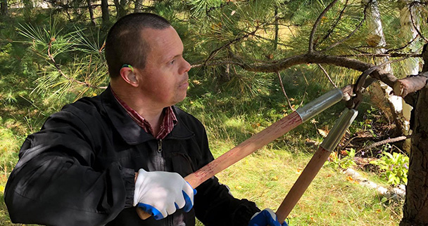 Man pruning a tree outside, L'Arche Sudbury